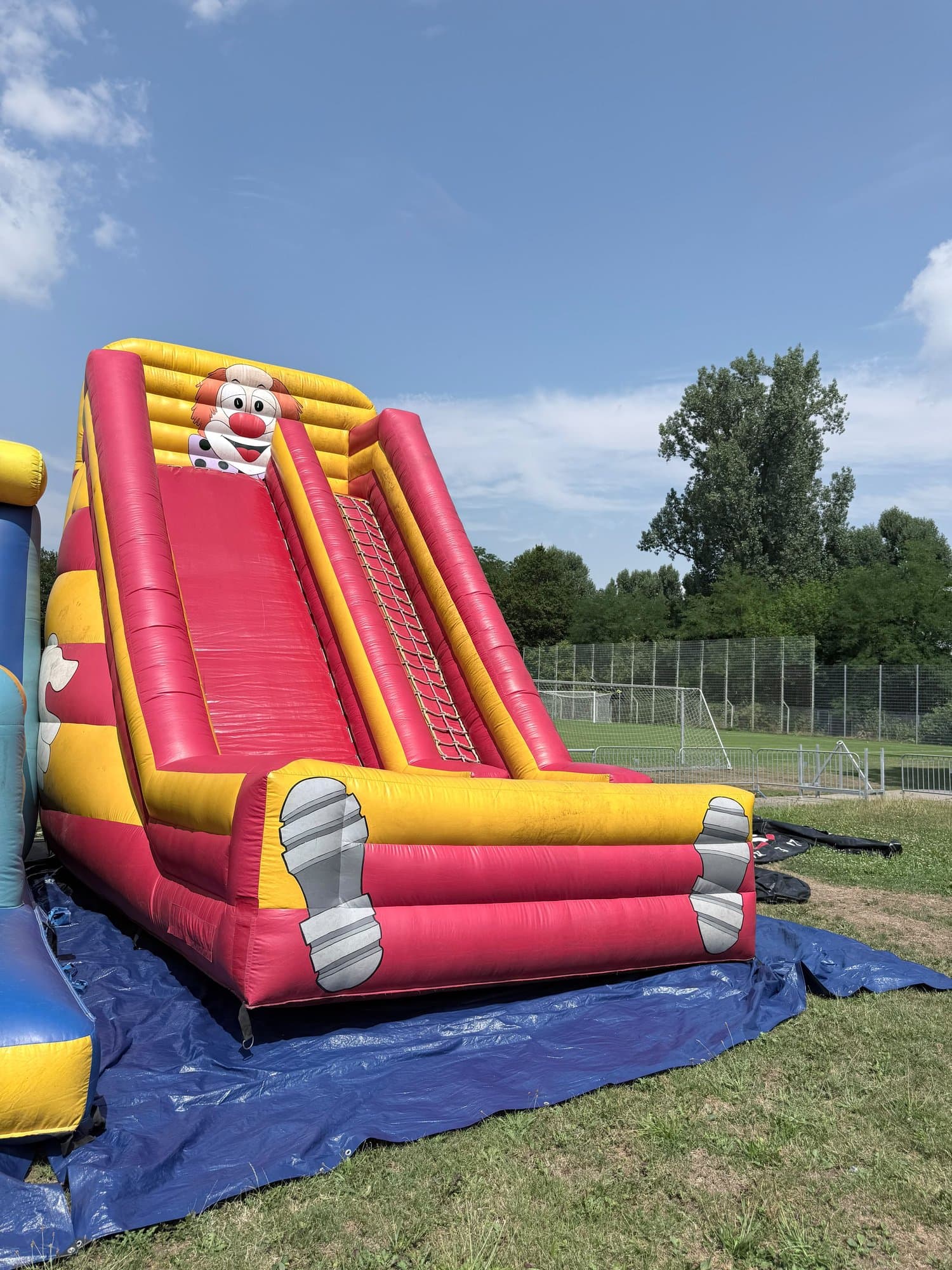 Riesenrutsche in Rot und Gelb mit Clown-Gesicht auf einer Wiese