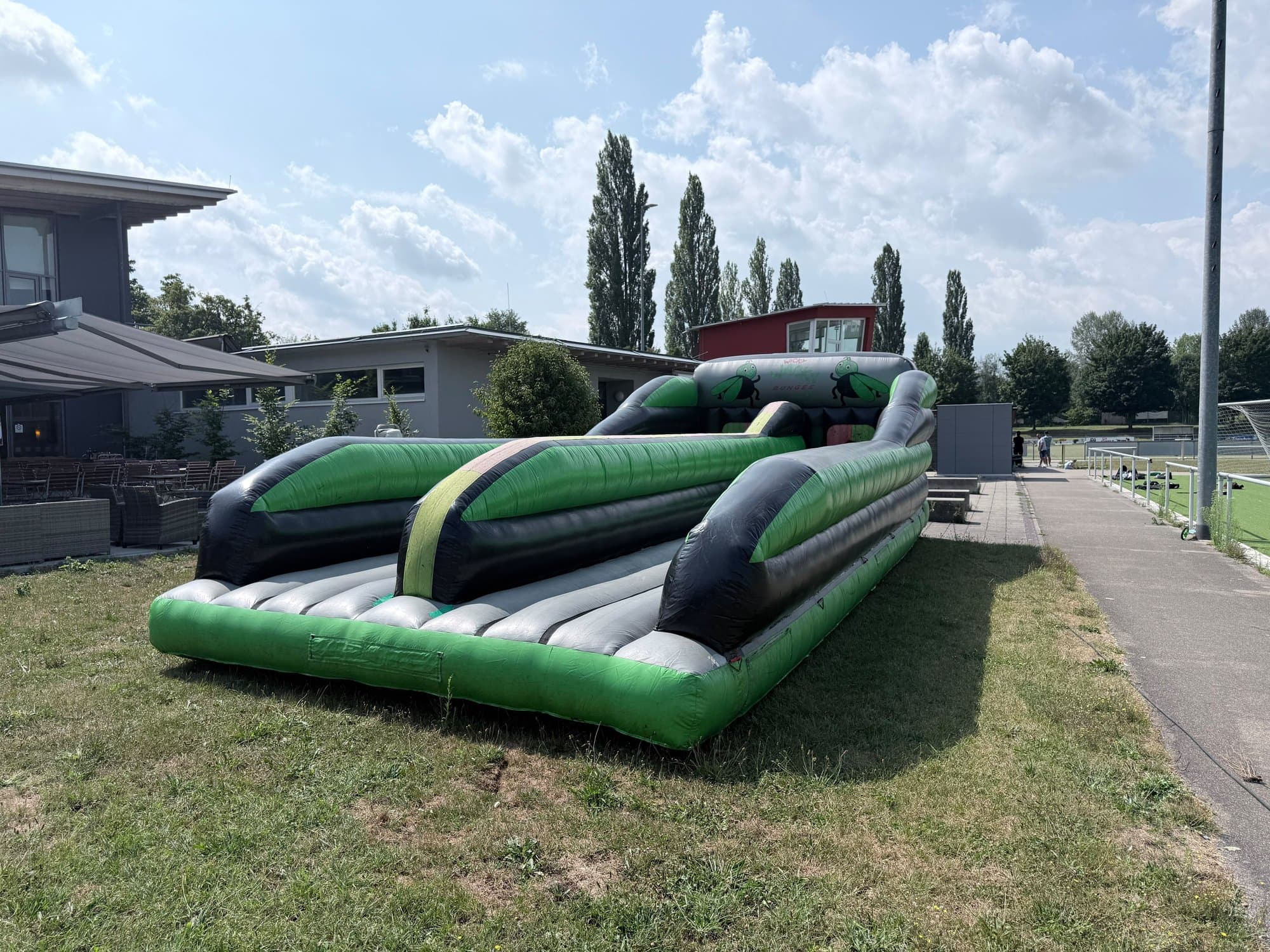 Grün-schwarzer BungeeRun mit zwei Bahnen auf einer Wiese an einem Vereinsheim