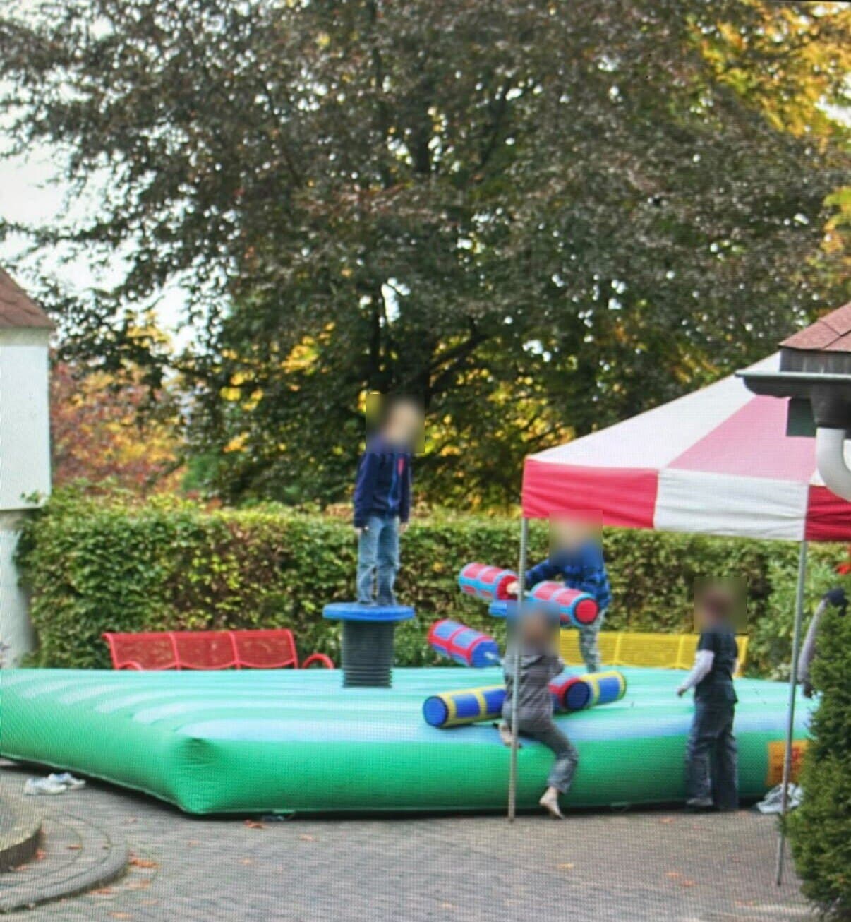Grünes Luftkissen mit einem Podest und weichen Polsterrollen, Kinder spielen darauf